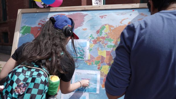 NFA students add pins to the world map, to signify their personal and familial homelands, during NFA Across the Globe.